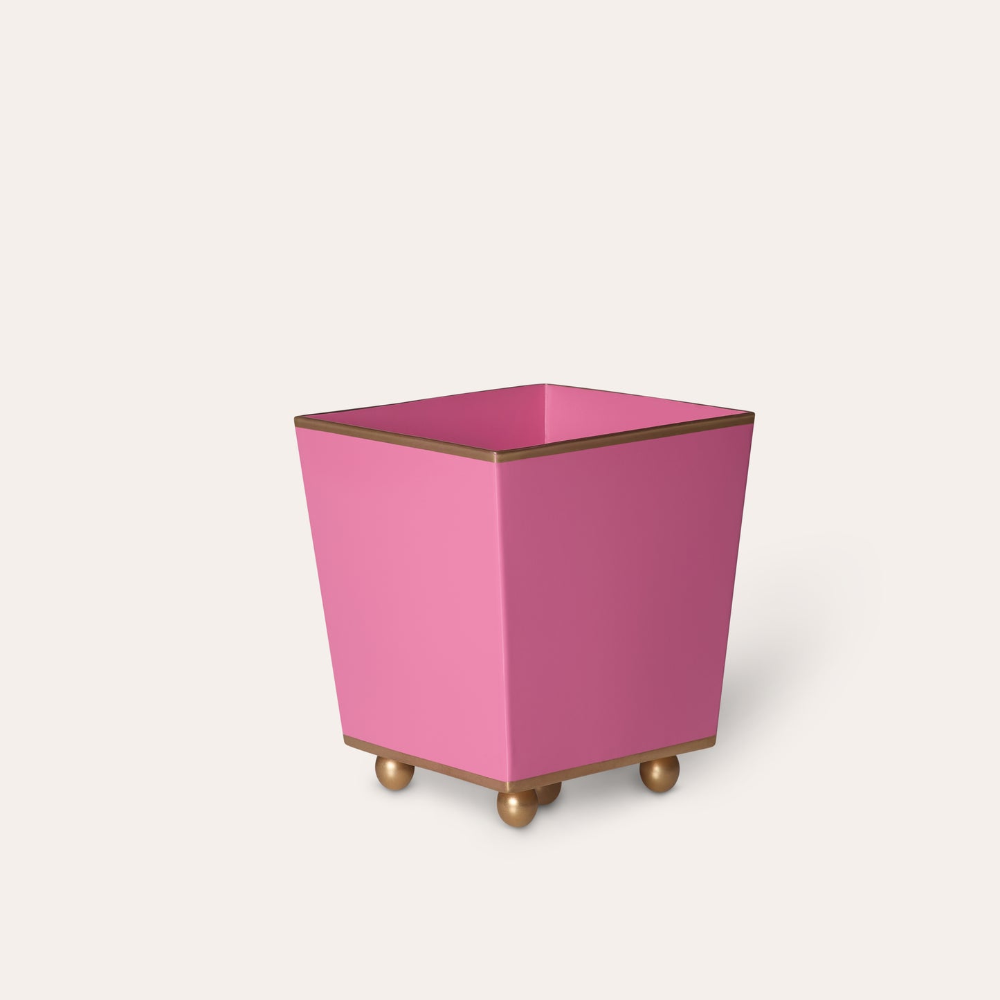 Pink rectangular planter with gold trim and ball feet on a white background