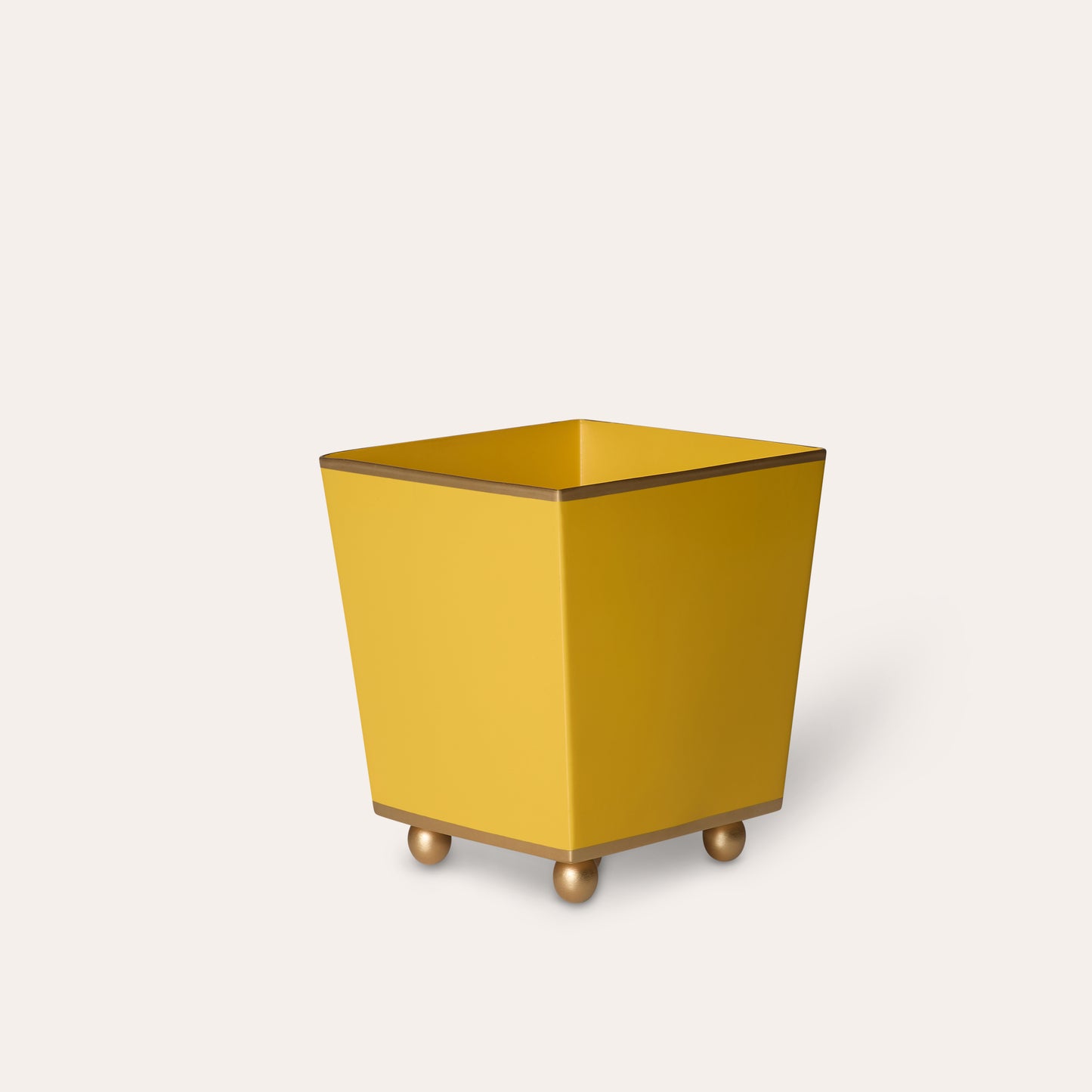 Yellow metal plant pot with gold edge and round feet on a white background