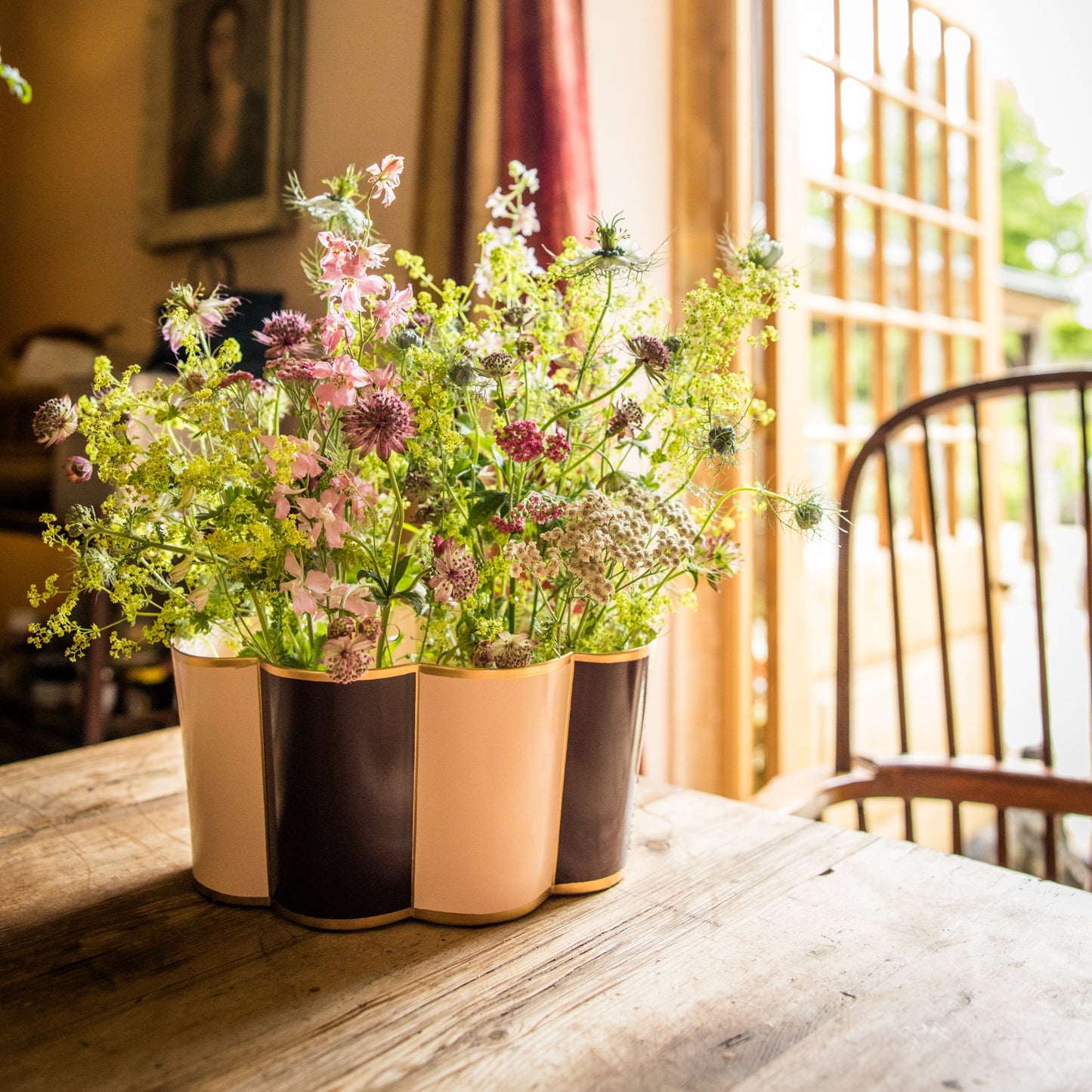 Large toleware planter with a wildflower arrangement  on a wooden dining table.