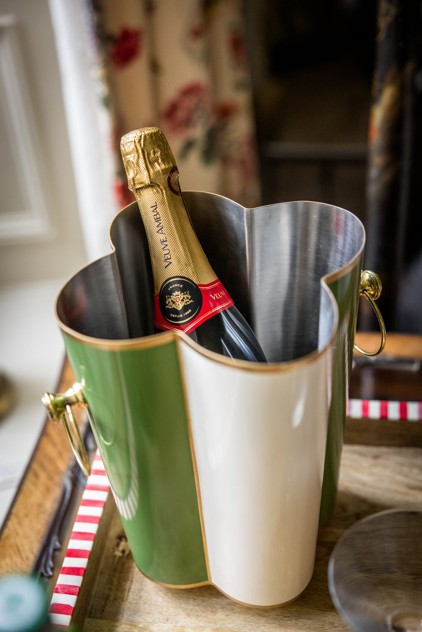 Bottle of champagne in a decorative scallop flower shaped ice bucket on a table.