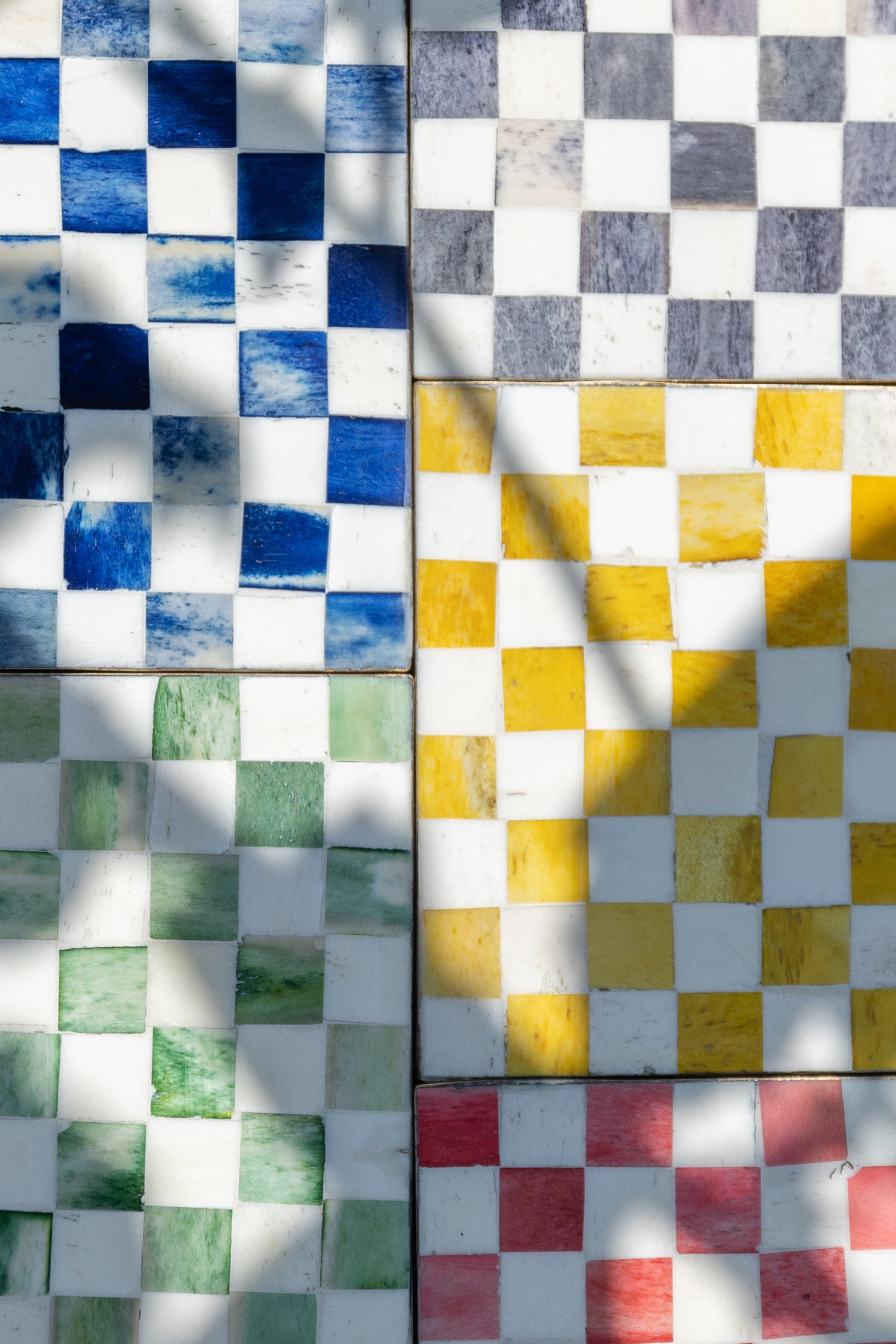 A close up of 5 check pattern bone inlay coasters in different colours (blue, grey, yellow, green and red).