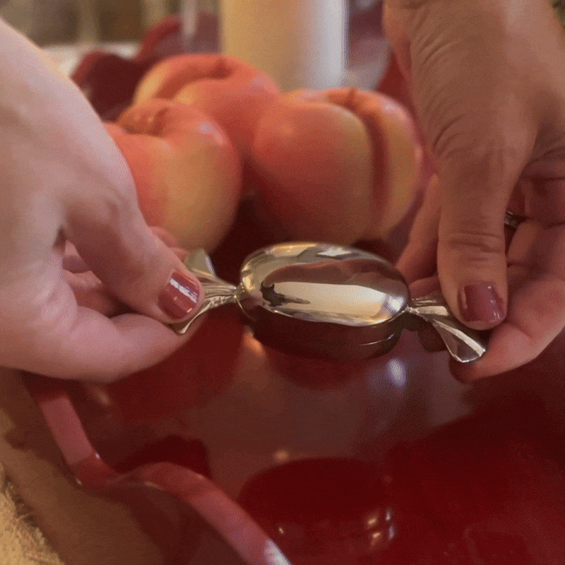 Candy shaped chrome silver hinged box being opened and closed by hands using the handles.