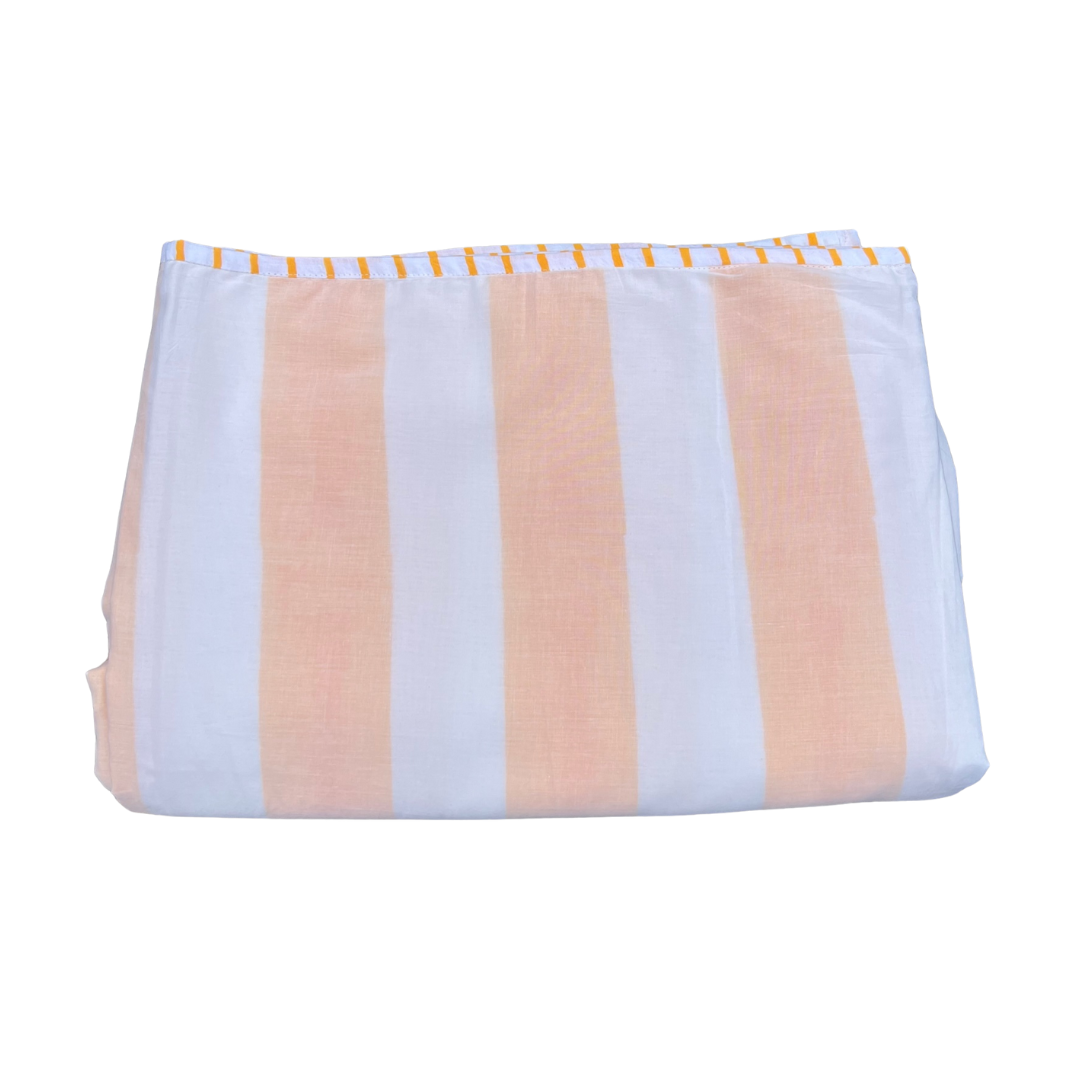Folded striped cotton blanket in orange yellow and white stripes with a decorative stitched edge trim.