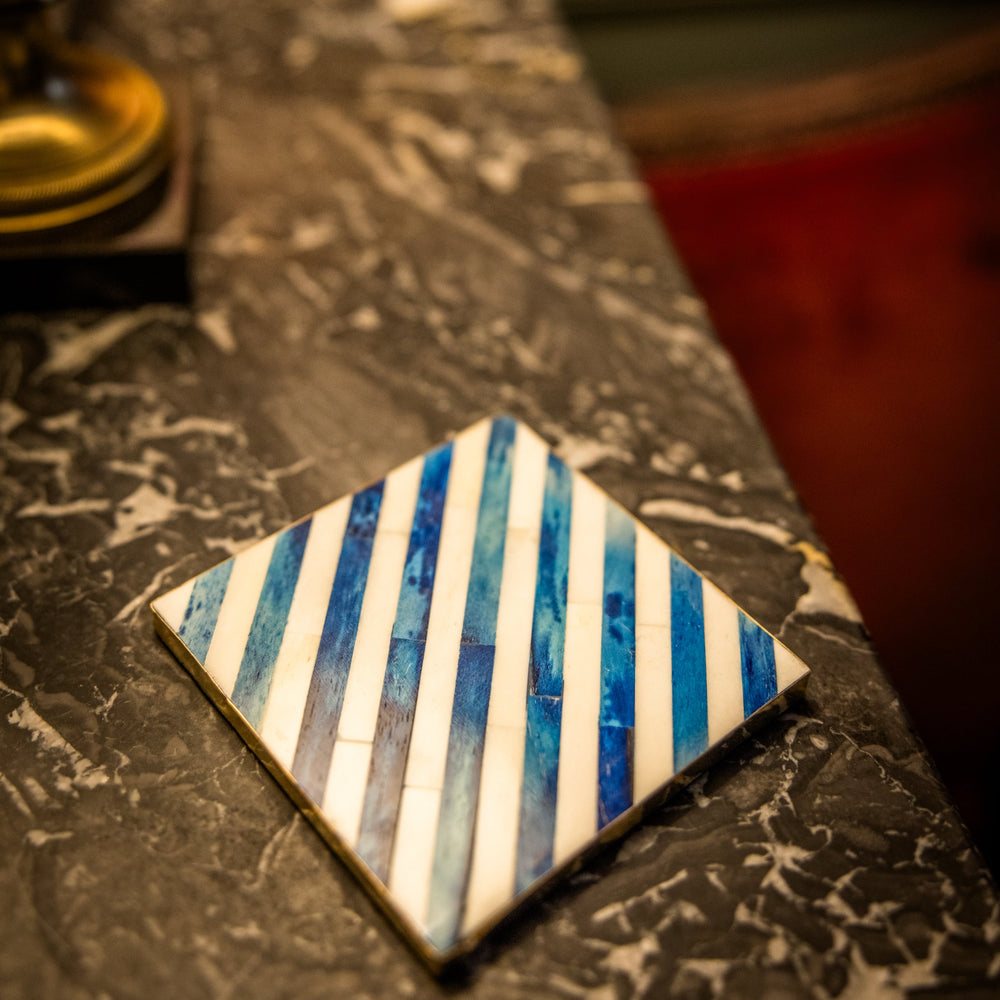 Decorative tile with blue and white stripes on a marble surface
