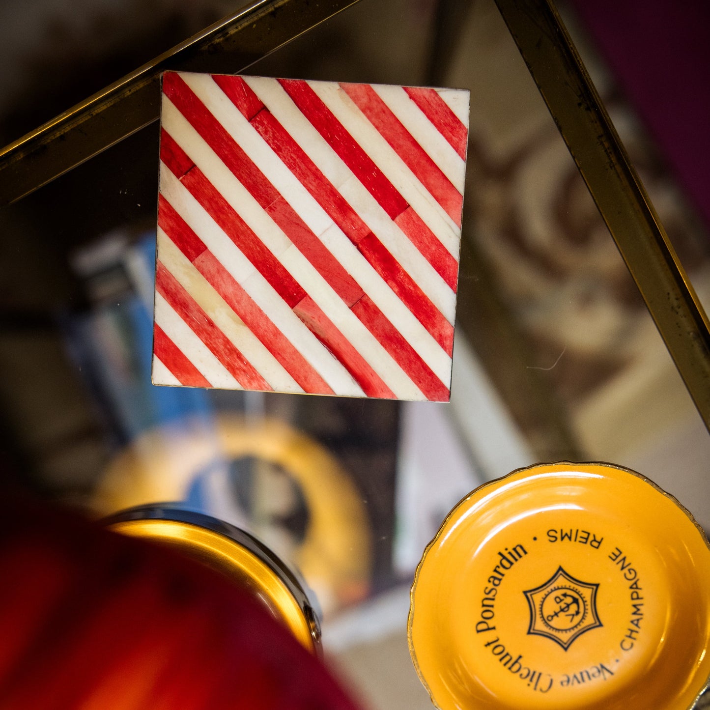 Close-up of a red and white striped coaster with a blurred bottle cap in the foreground.