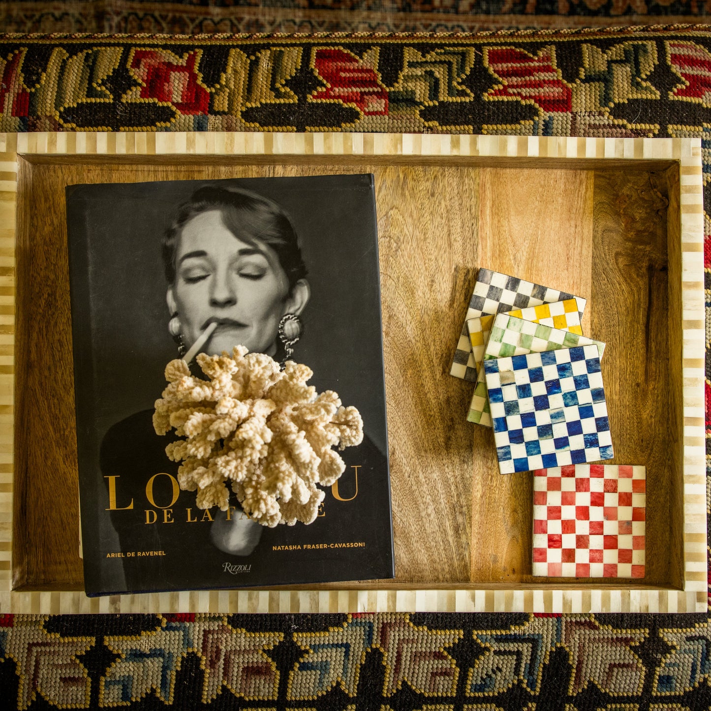 Framed artwork with a book titled 'L'Or de la Vie' and decorative items on a patterned rug.