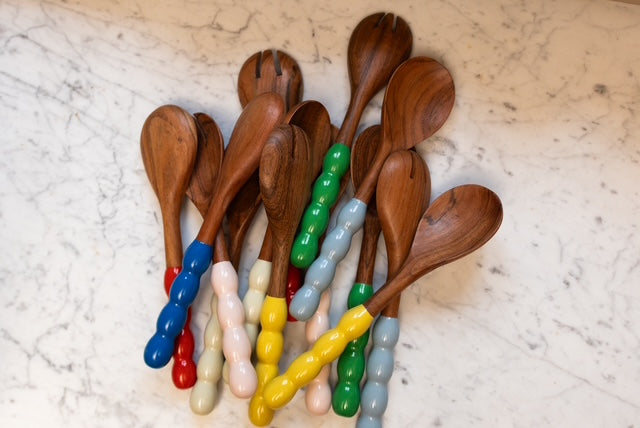 Wooden spoons with colorful handles on a marble surface
