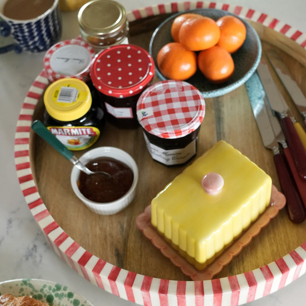 Breakfast setting with croissants, jam, and oranges on a checkered tablecloth.