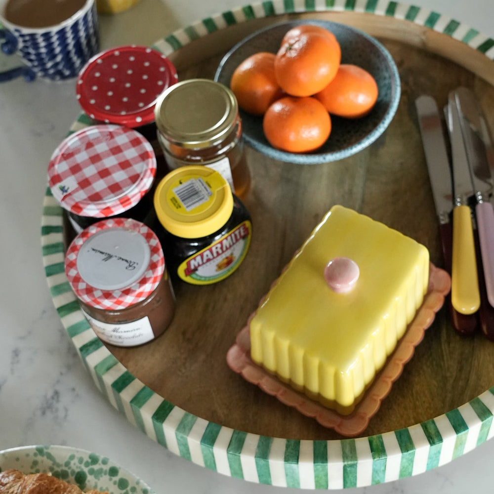 Table setting with jam jars, a cake, and fruit on a checkered tray.