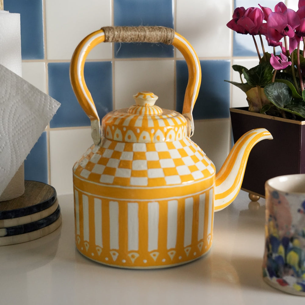 Yellow and white checkered teapot with striped pattern on a kitchen counter.